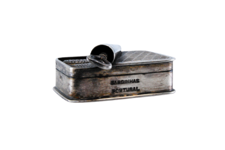 Caixa de comprimidos em prata em forma de lata de sardinhas com tampa basculante.